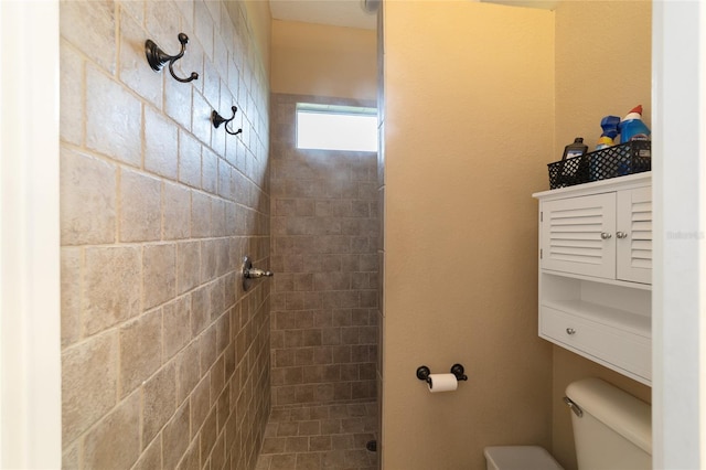 bathroom featuring tiled shower and toilet