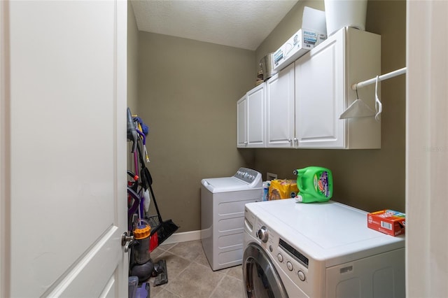 washroom featuring washer and clothes dryer, a textured ceiling, light tile patterned floors, and cabinets