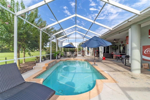 view of pool featuring glass enclosure, a patio, and ceiling fan