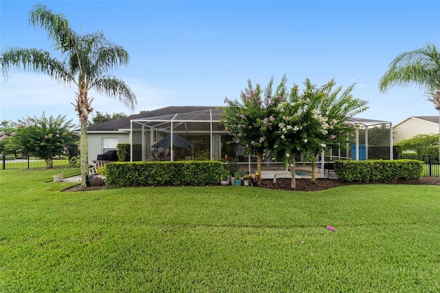 rear view of property with glass enclosure and a lawn