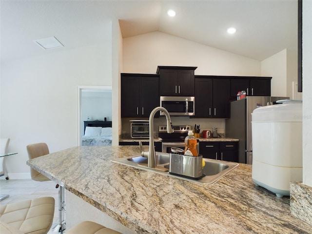 kitchen with a kitchen bar, stainless steel appliances, lofted ceiling, and sink