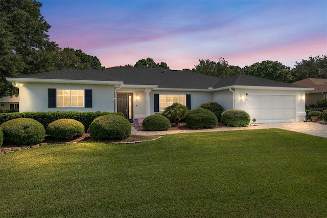 ranch-style home featuring a garage and a lawn