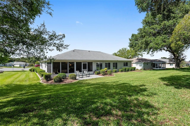 back of property with a sunroom, a patio area, and a lawn