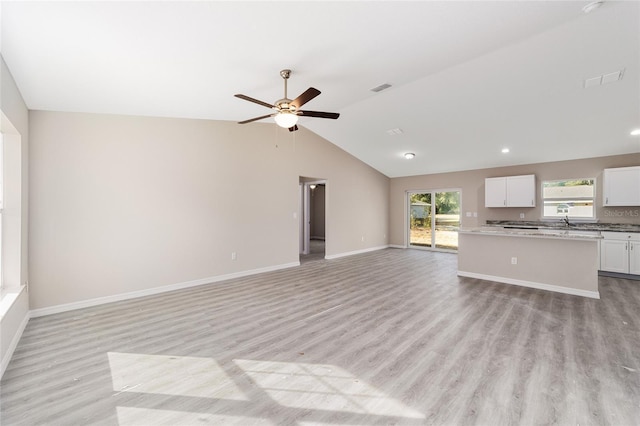 unfurnished living room featuring ceiling fan, vaulted ceiling, and light hardwood / wood-style flooring