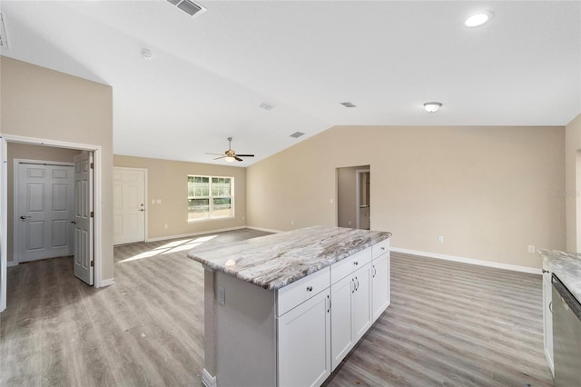 kitchen featuring ceiling fan, dishwasher, a kitchen island, white cabinetry, and light stone counters