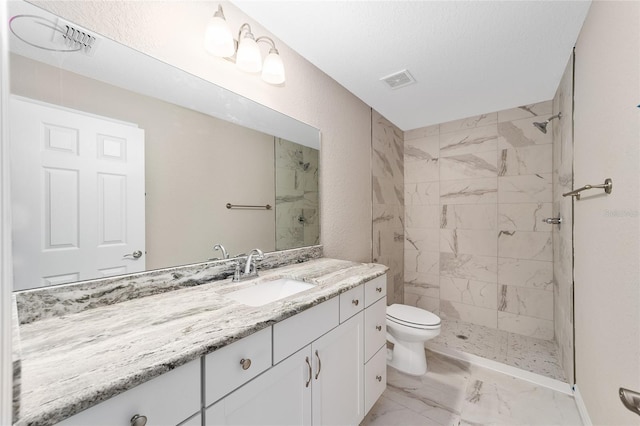 bathroom featuring a textured ceiling, toilet, vanity, and a tile shower