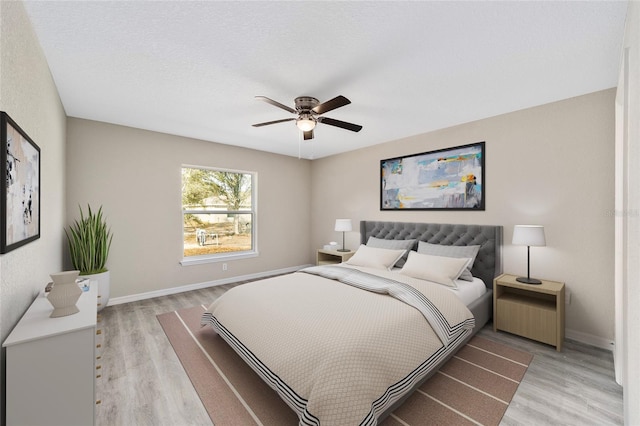 bedroom with a textured ceiling, ceiling fan, and light hardwood / wood-style flooring