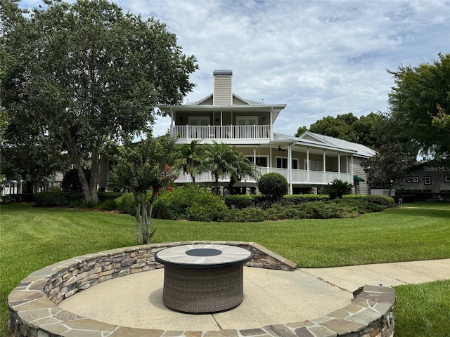 back of property featuring an outdoor fire pit and a lawn