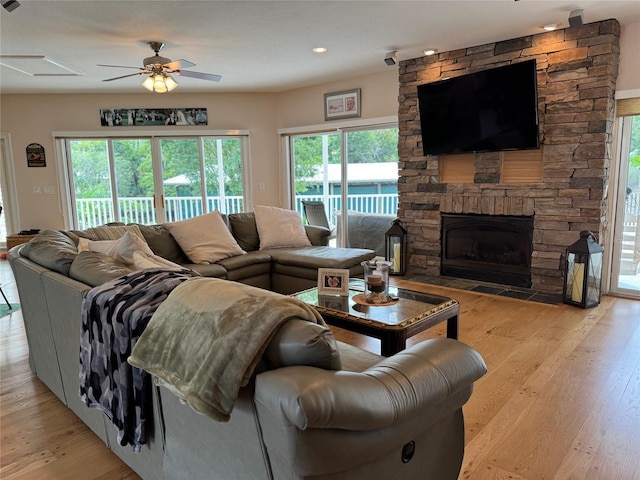 living room featuring ceiling fan, a fireplace, a healthy amount of sunlight, and light wood-type flooring