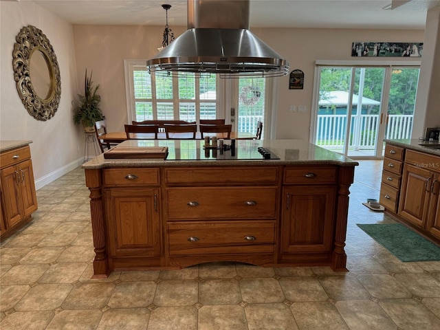 kitchen featuring island exhaust hood, black electric stovetop, decorative light fixtures, and stone countertops