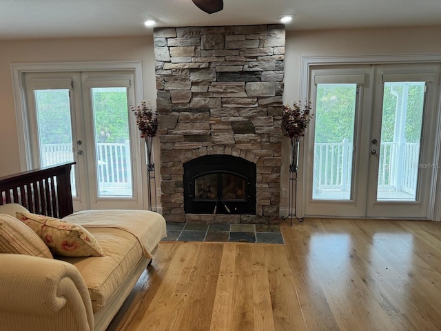 living room with hardwood / wood-style flooring, a healthy amount of sunlight, and a stone fireplace