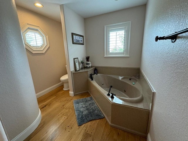 bathroom featuring wood-type flooring, toilet, and a bathtub