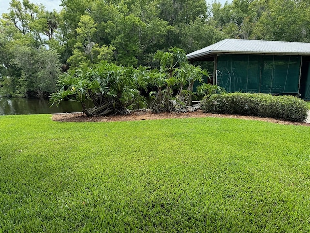 view of yard featuring a sunroom and a water view