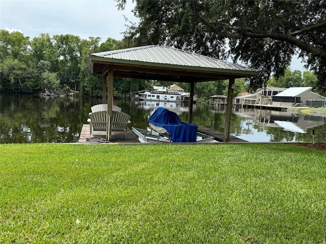 view of dock with a lawn and a water view