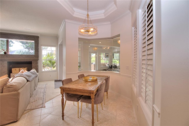 tiled dining room featuring crown molding, a fireplace, and a raised ceiling