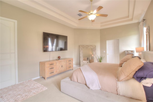 carpeted bedroom featuring a raised ceiling and ceiling fan