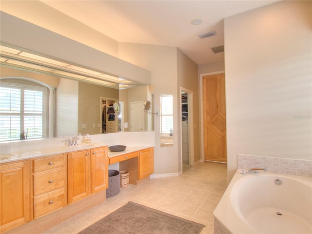 bathroom with tile patterned flooring, vanity, and tiled bath