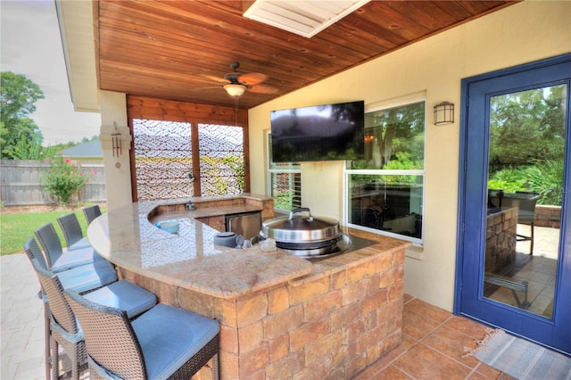 view of patio featuring an outdoor kitchen, ceiling fan, and a bar