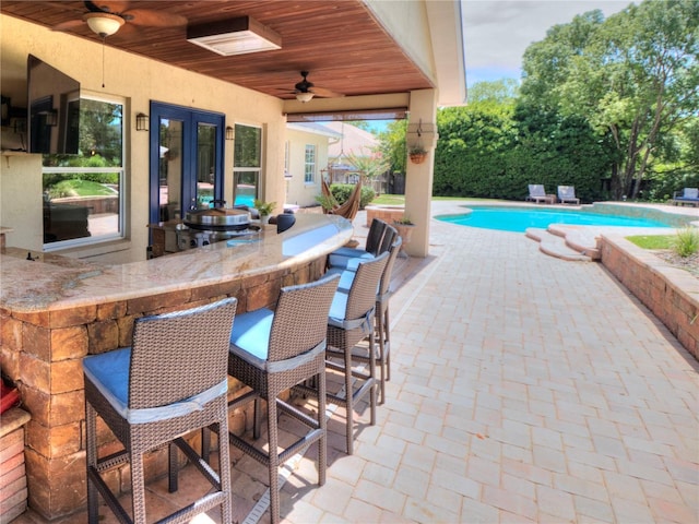 view of pool featuring ceiling fan, an outdoor bar, and a patio area