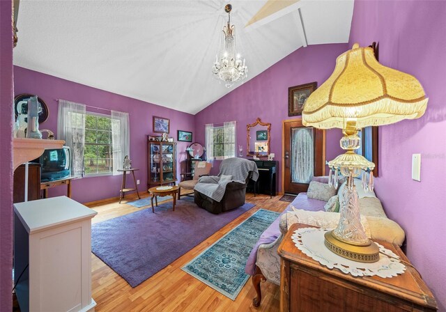 living room with a chandelier, a fireplace, light hardwood / wood-style floors, and vaulted ceiling