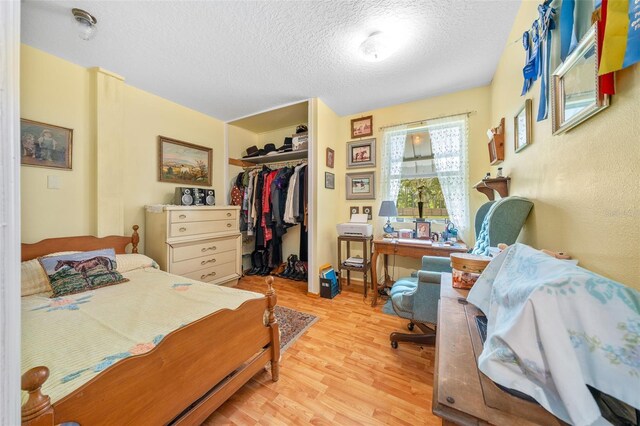 bedroom featuring light hardwood / wood-style floors, a textured ceiling, and a closet