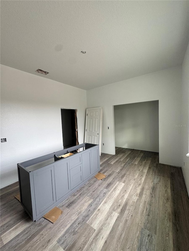 unfurnished living room featuring a textured ceiling and light hardwood / wood-style flooring