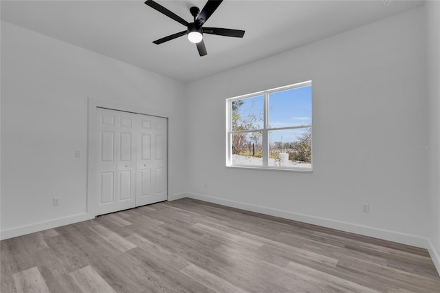 unfurnished bedroom featuring light hardwood / wood-style flooring, ceiling fan, and a closet