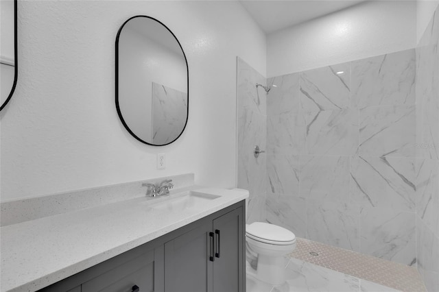 bathroom with toilet, tiled shower, and vanity