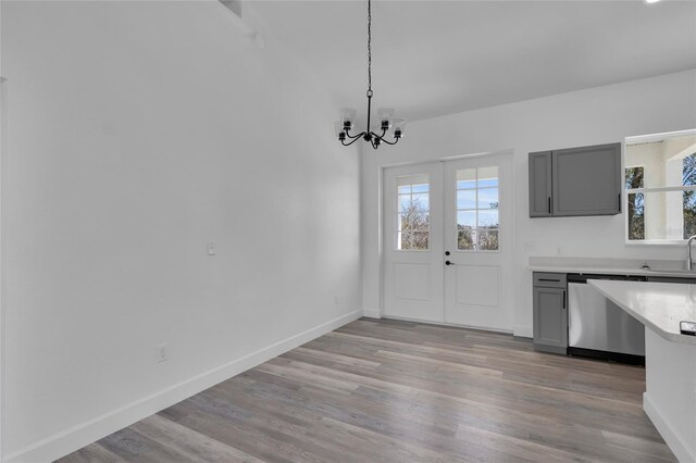 unfurnished dining area featuring light hardwood / wood-style floors, french doors, sink, and a notable chandelier