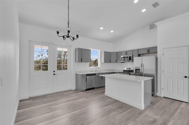 kitchen featuring light hardwood / wood-style flooring, hanging light fixtures, stainless steel appliances, gray cabinets, and a kitchen island