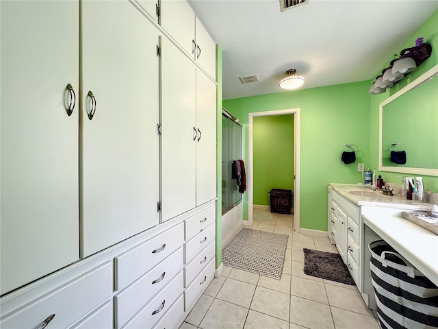 bathroom with tile patterned flooring, vanity, and bath / shower combo with glass door