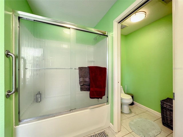 bathroom featuring bath / shower combo with glass door, tile patterned floors, and toilet