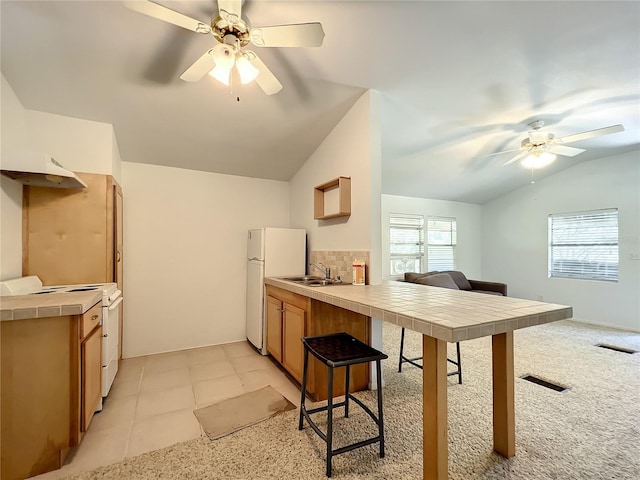 kitchen featuring sink, vaulted ceiling, electric range, tile counters, and white fridge