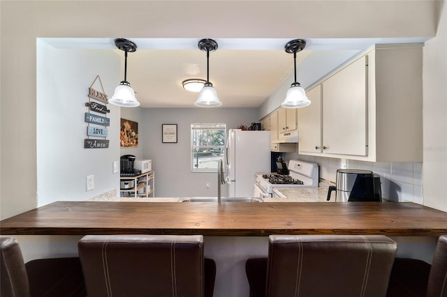 kitchen with white appliances, backsplash, sink, decorative light fixtures, and kitchen peninsula