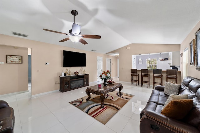 living room with ceiling fan, light tile patterned floors, a fireplace, and vaulted ceiling