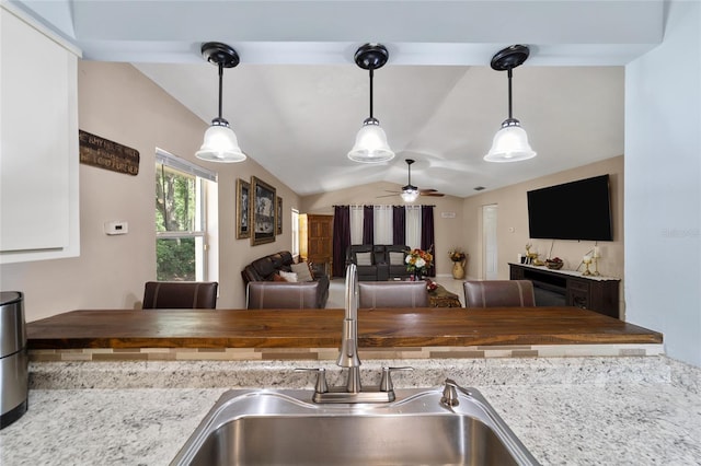 kitchen featuring butcher block counters, ceiling fan, sink, decorative light fixtures, and lofted ceiling