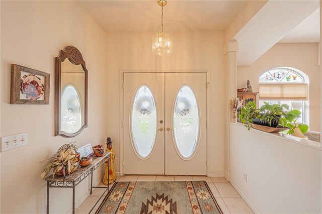 tiled entrance foyer with french doors and a notable chandelier