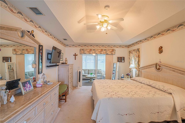 carpeted bedroom with vaulted ceiling, a raised ceiling, ceiling fan, and a textured ceiling