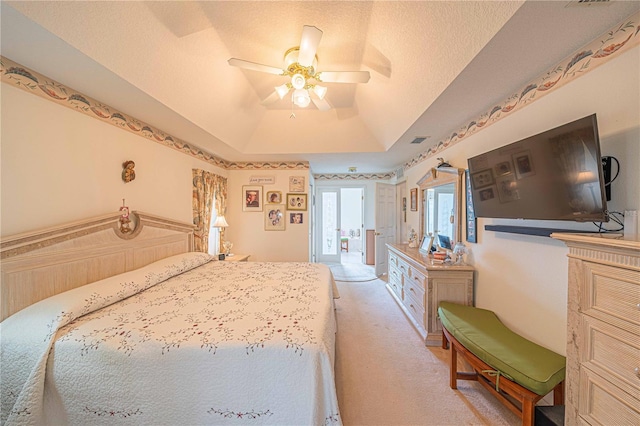 bedroom featuring a textured ceiling, ceiling fan, light carpet, and a tray ceiling