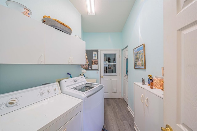 laundry room featuring washer and dryer, cabinets, and wood-type flooring