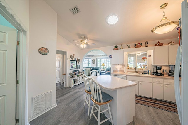 kitchen featuring dark wood-type flooring, sink, hanging light fixtures, ceiling fan, and white cabinetry