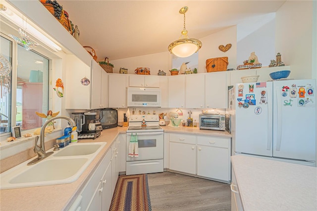 kitchen featuring sink, hanging light fixtures, vaulted ceiling, white appliances, and white cabinets