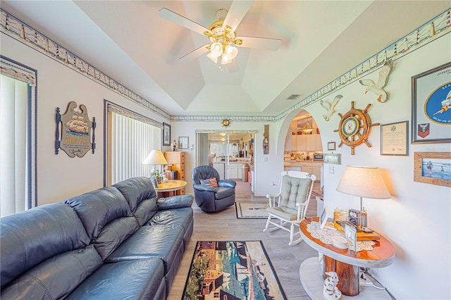 living room featuring ceiling fan, wood-type flooring, lofted ceiling, and a tray ceiling