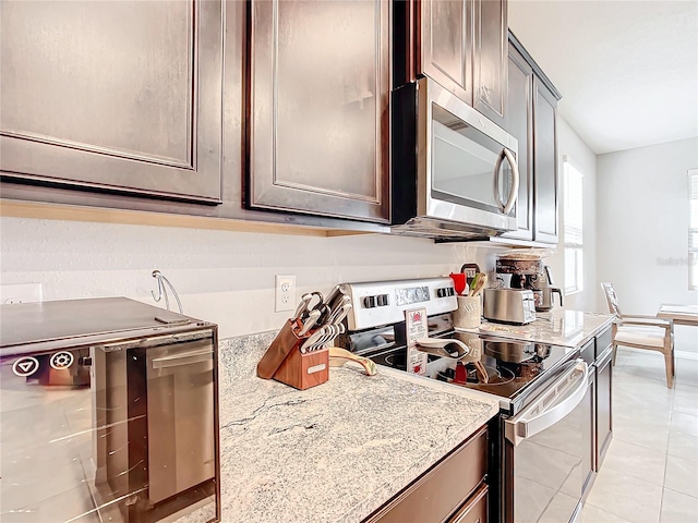 kitchen with light stone counters, light tile patterned floors, and stainless steel appliances