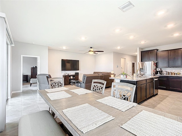 dining space featuring ceiling fan, sink, and light tile patterned floors