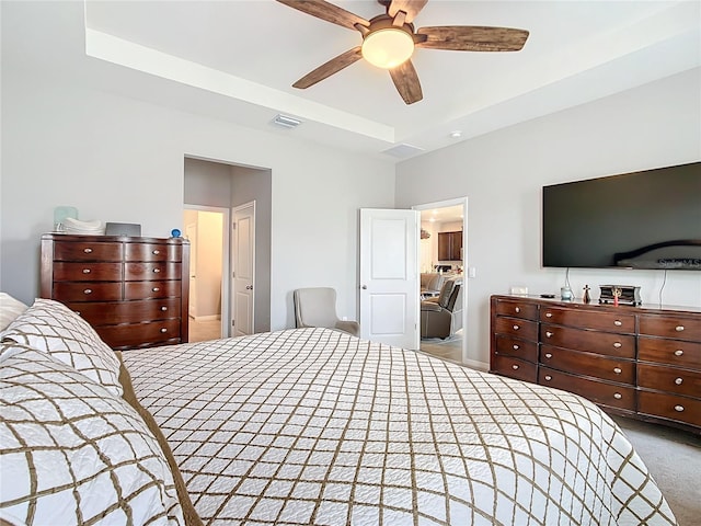 carpeted bedroom featuring ceiling fan and a tray ceiling