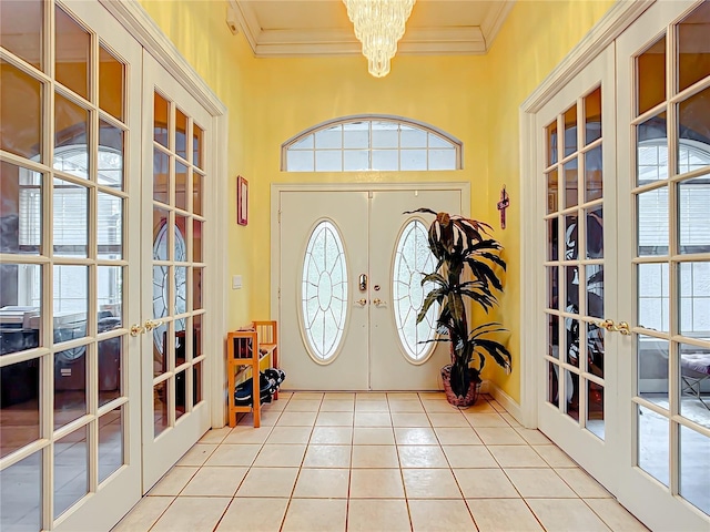 tiled entrance foyer with crown molding, french doors, and an inviting chandelier