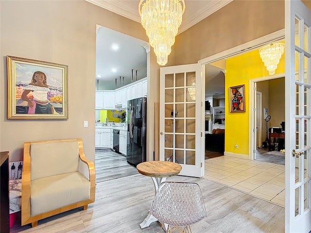 sitting room featuring crown molding, french doors, light hardwood / wood-style floors, and an inviting chandelier