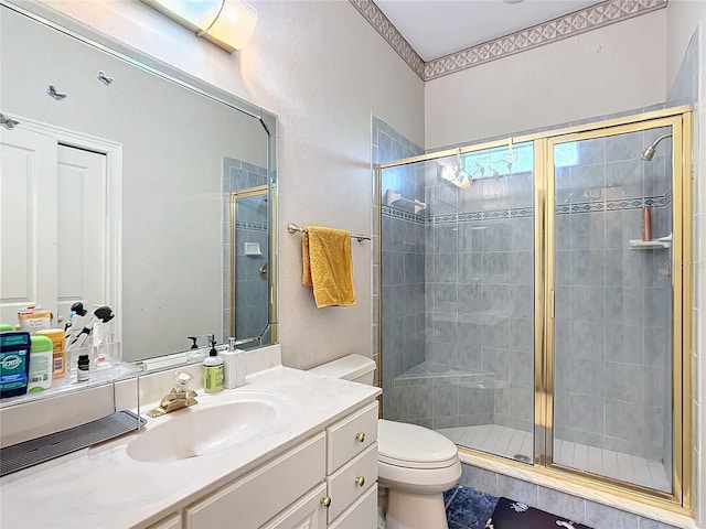 bathroom with vanity, a shower with shower door, and toilet