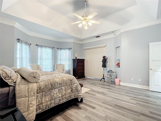 bedroom with a raised ceiling, ceiling fan, ornamental molding, and light wood-type flooring